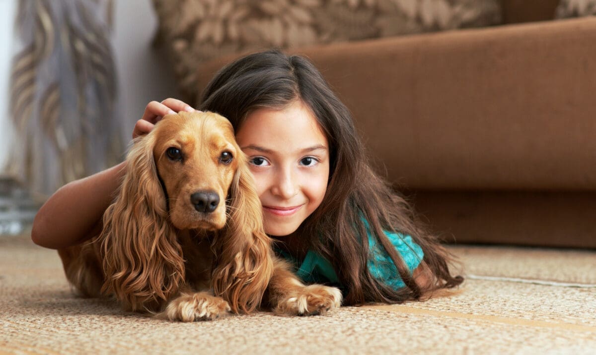 A girl lies on the floor with a dog