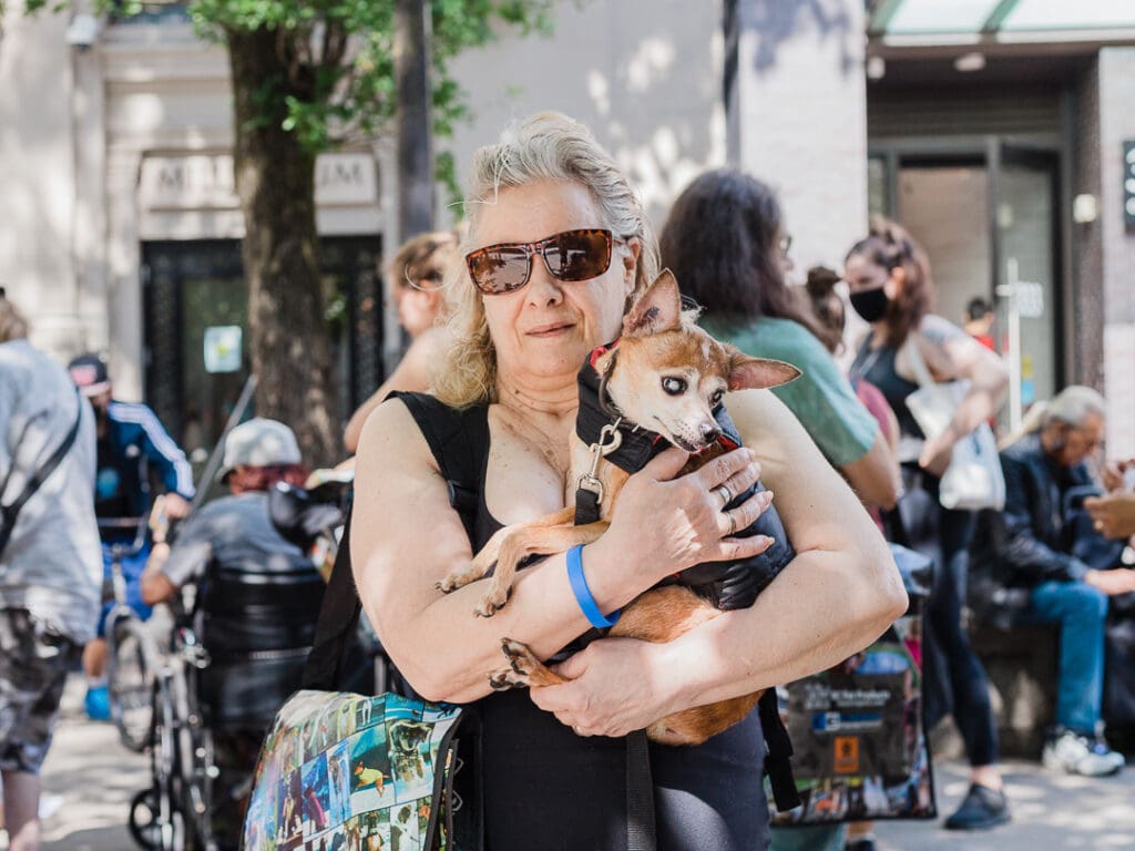 A person holds a chihuahua wearing a coat.