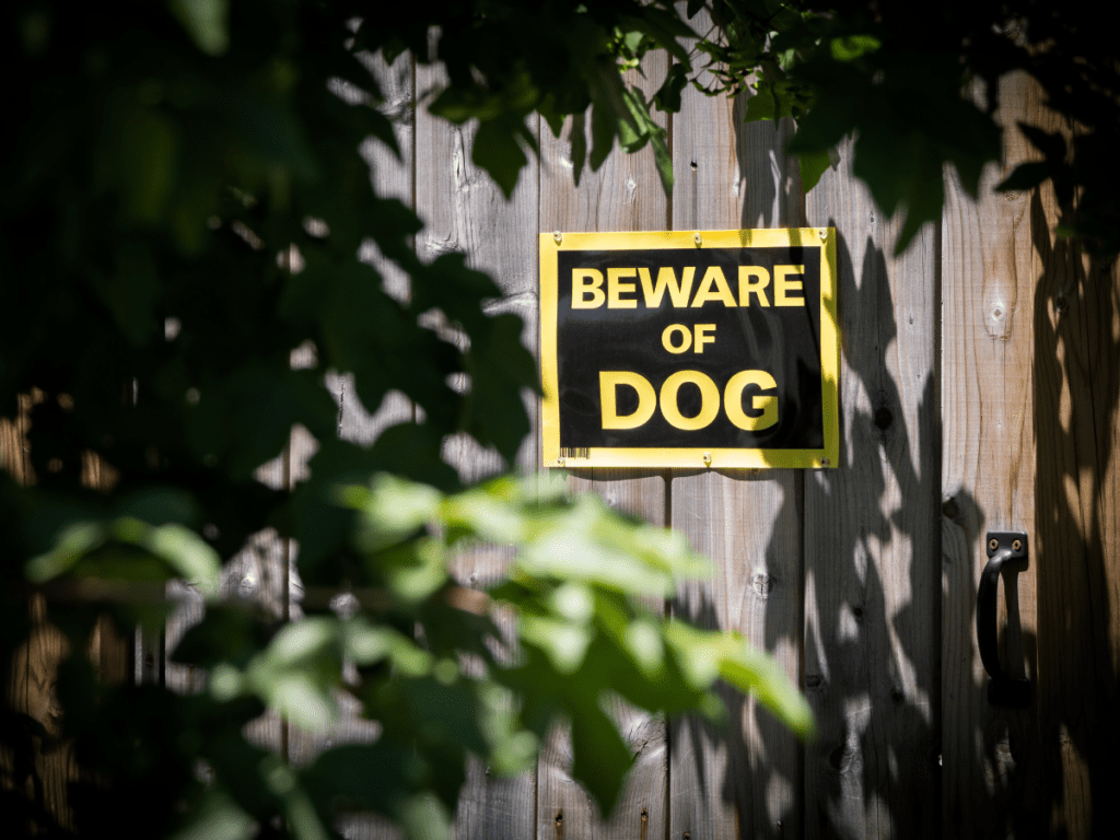 A beware of dog sign on a personal property fence.