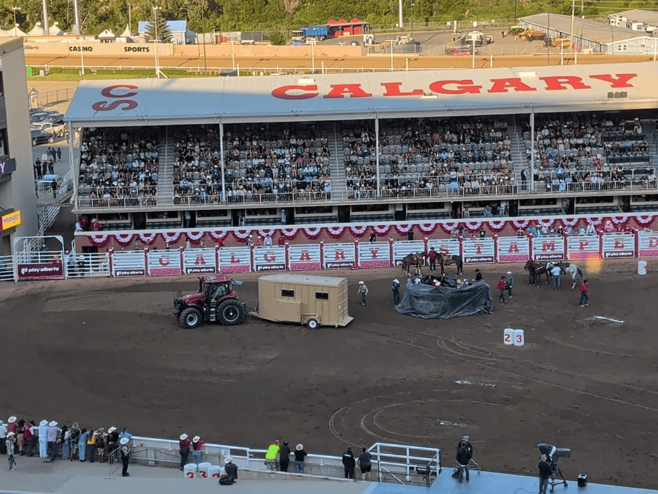 a horse being lifted into a trailer behind a privacy tarp on the track.