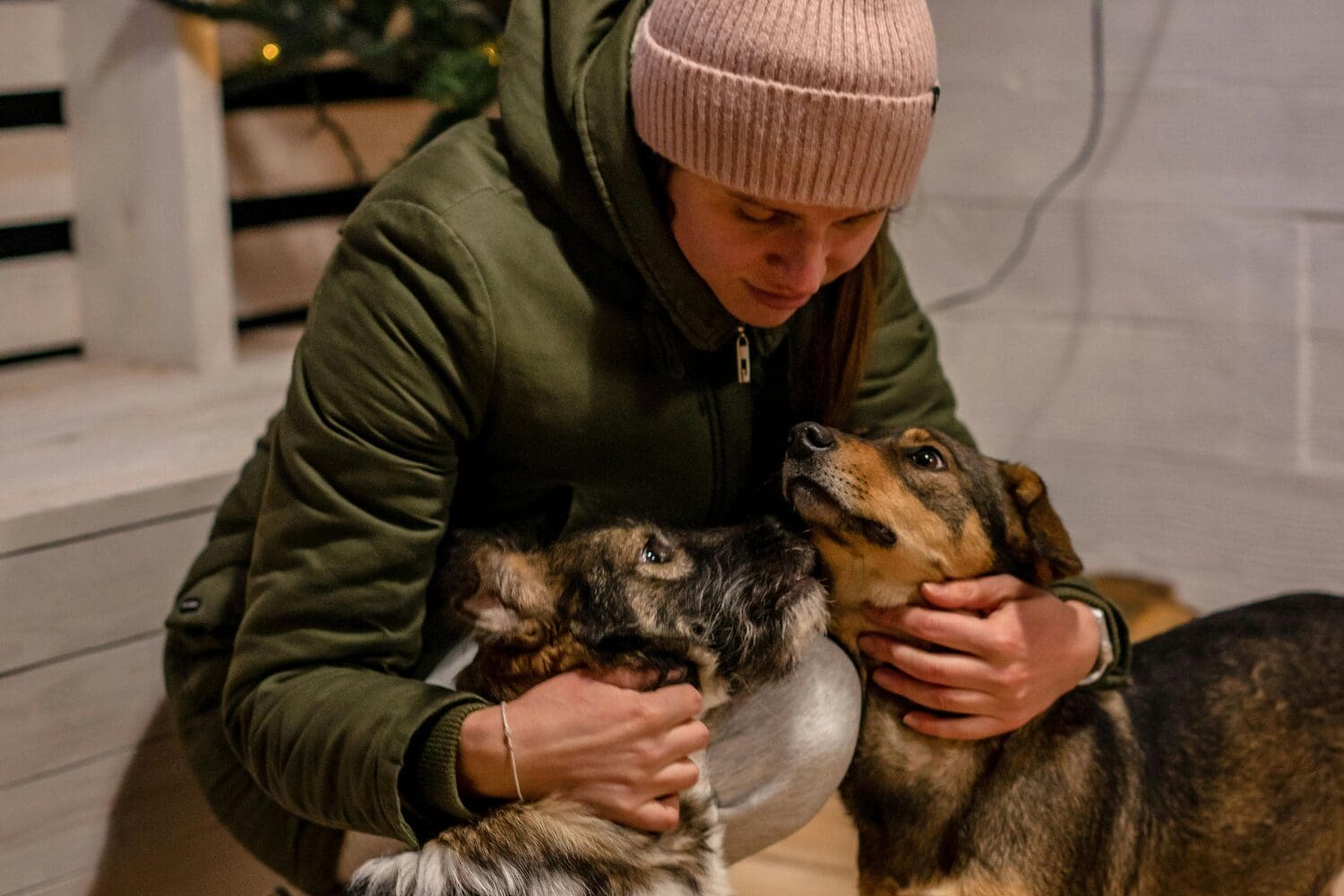 A person outside cuddling two dogs